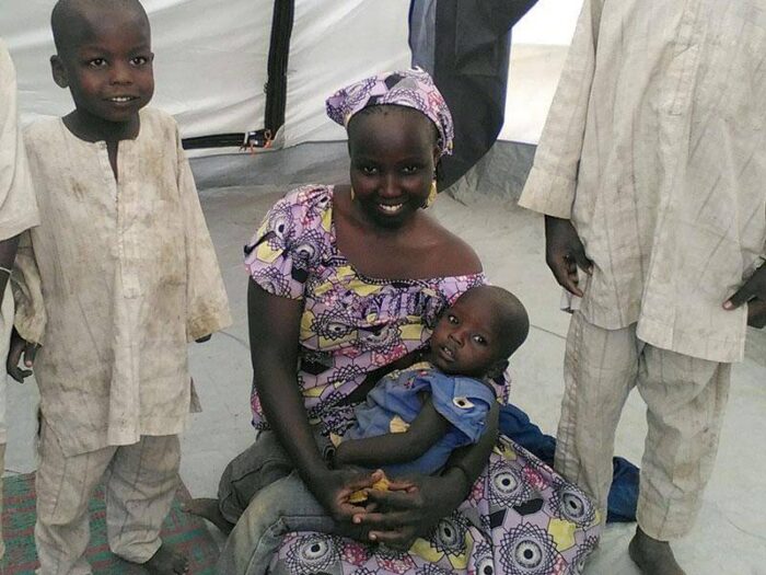 Woman sits on floor of ShelterBox tent surrounded by children