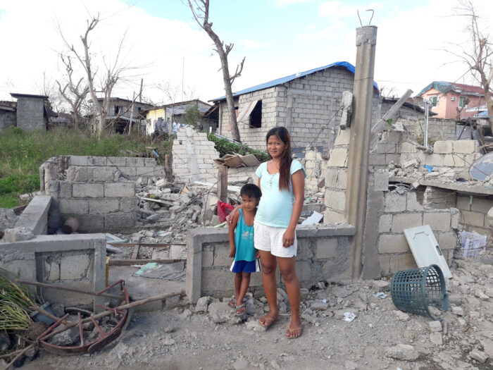 Mother and son stand outside destroyed home after Typhoon Mankhut in the Philippines