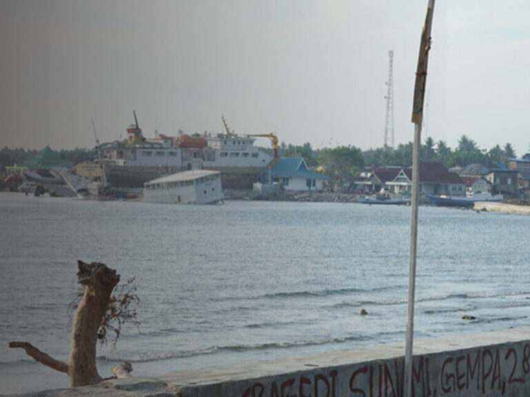 Man and woman standing near water after tsunami in Indonesia - banner