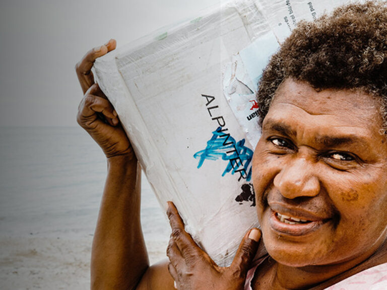 woman smiling and carrying a box on her right shoulder
