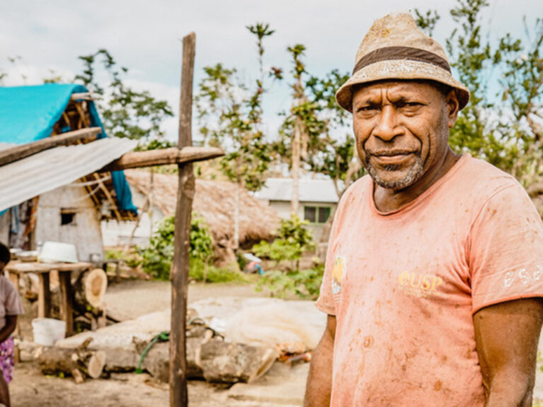 A man in Vanuatu standing around temporary shelters