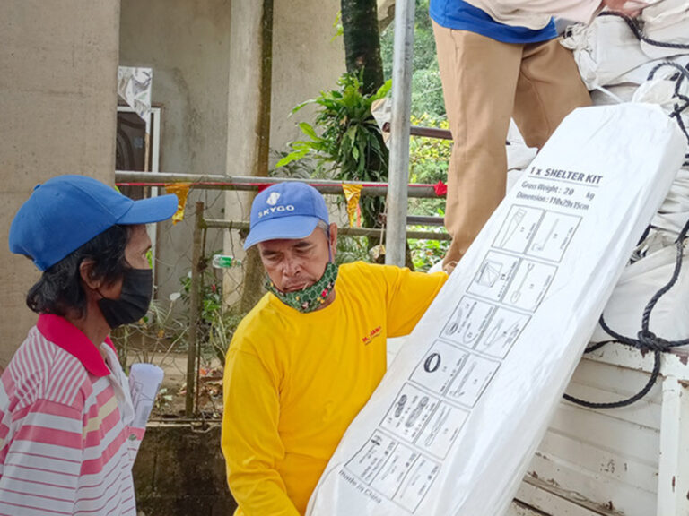 people unloading shelter kits off a truck in the Philippines after Typhoon Rai