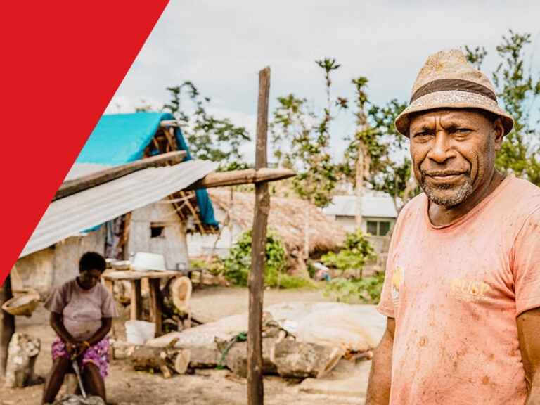 vanuatu man stands outside repaired home after storm