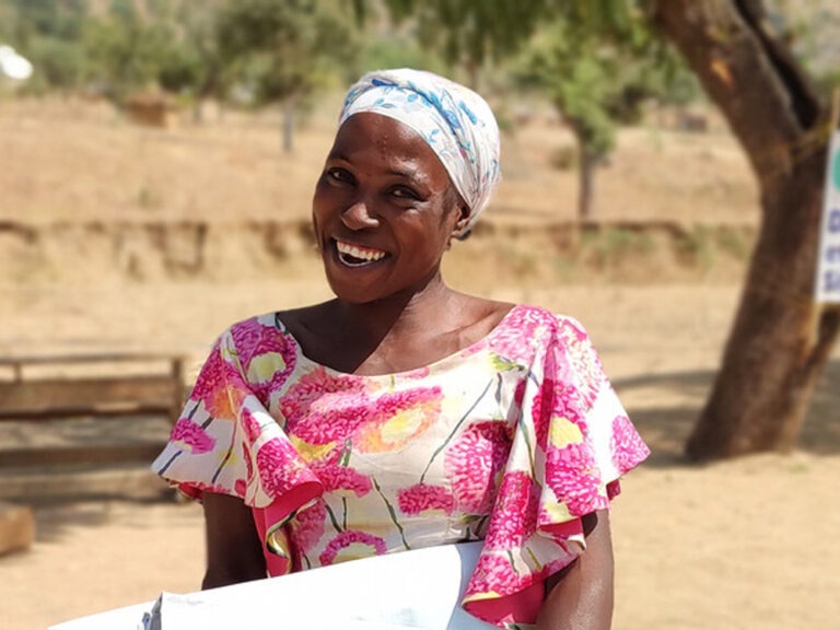 Woman smiling and carrying aid in Cameroon