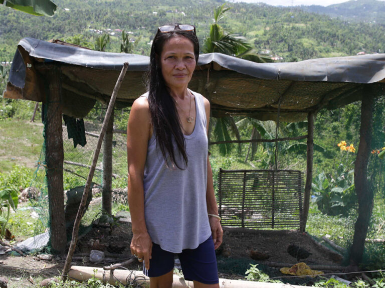 Woman standing next to damaged building after a Tropical Storm in Vanuatu