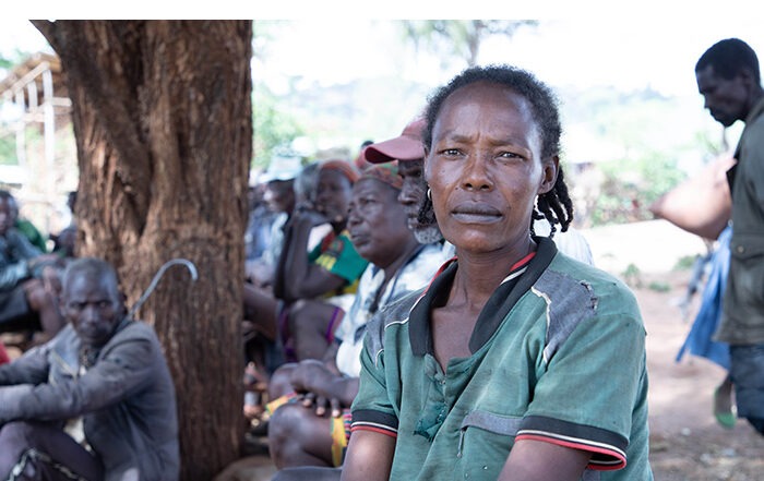 Woman in green sitting on the floor in Ethiopia, with many others sitting on the floor behind her.