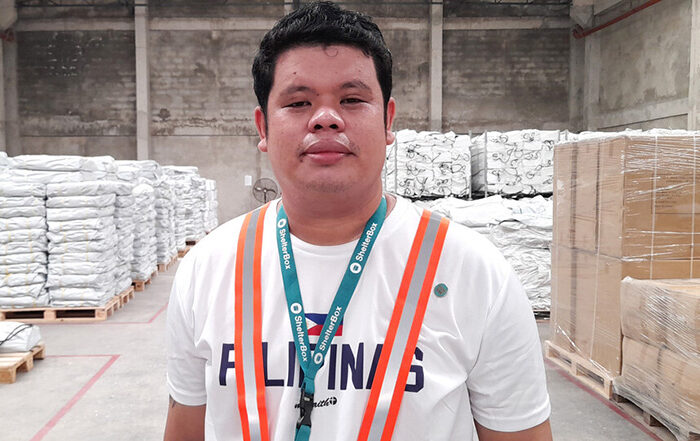 Man standing in from of aid materials inside the ShelterBox Operations Philippines warehouse