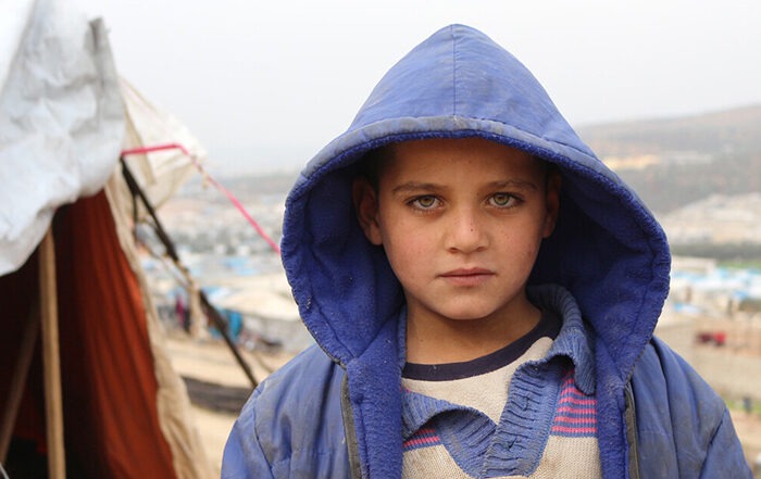 Close up image of a child in a winter coat in front of a tent