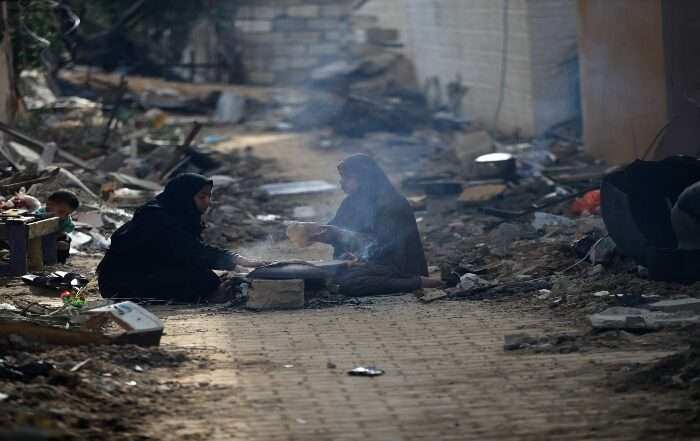 Two women sitting in the street after losing their homes in Gaza