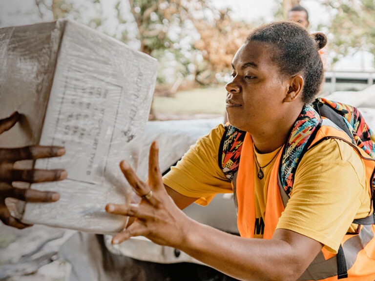 Woman passes box of aid in Vanuatu
