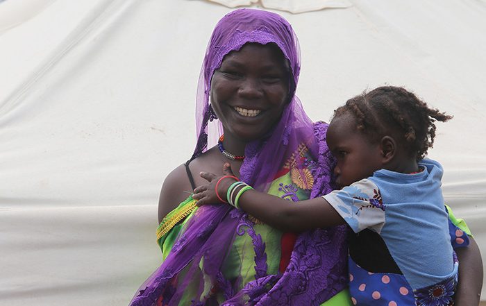 Woman holding a young child in front of a tent in Chad