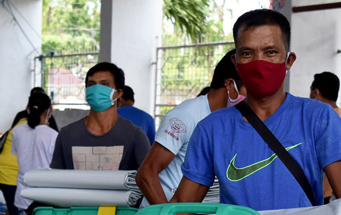 Men wearing facemasks carrying aid in the Philippines